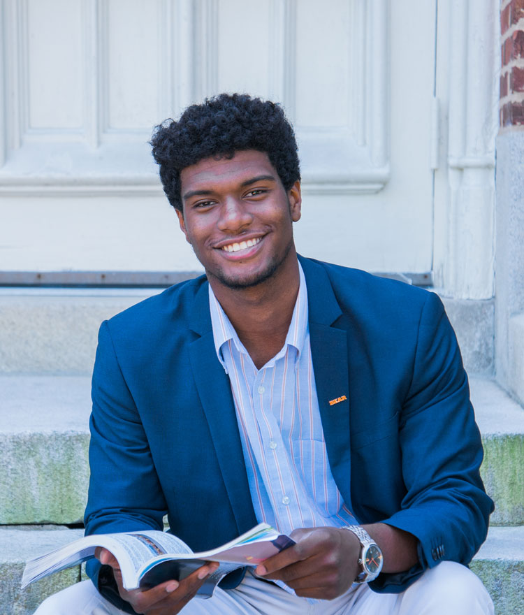 Student sitting on a step and holding a book