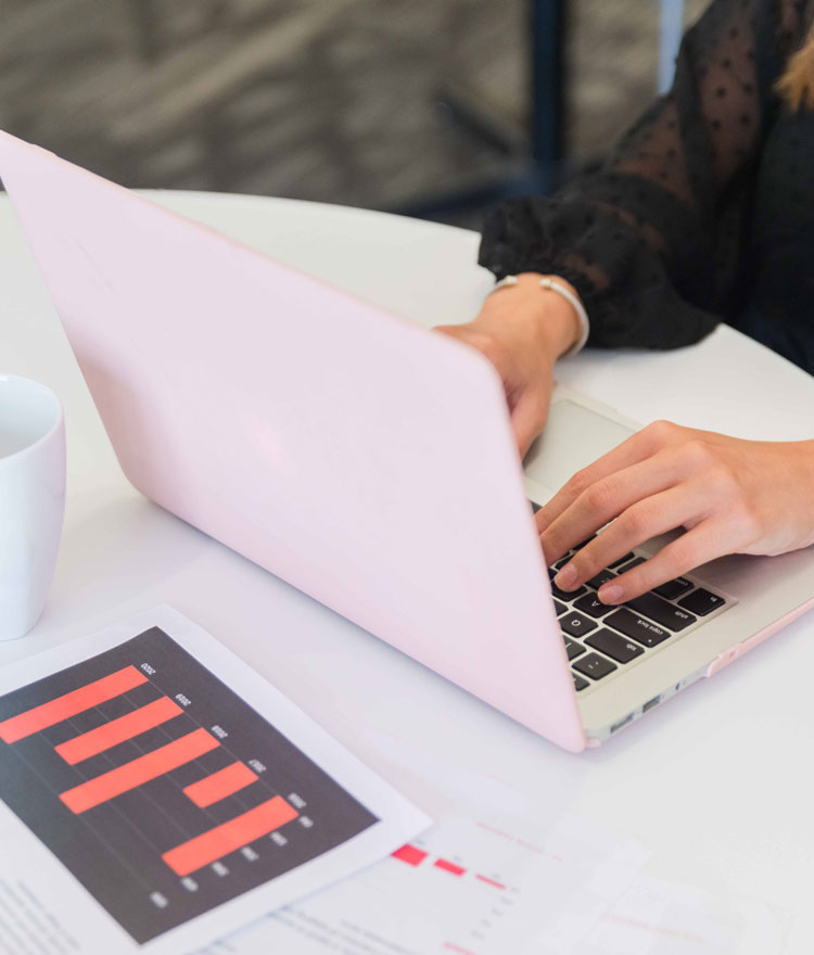 Hands on a laptop with a printed bar graph chart in front