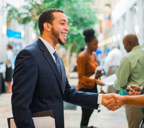 Smiling person shakes someone's hand in the University Center