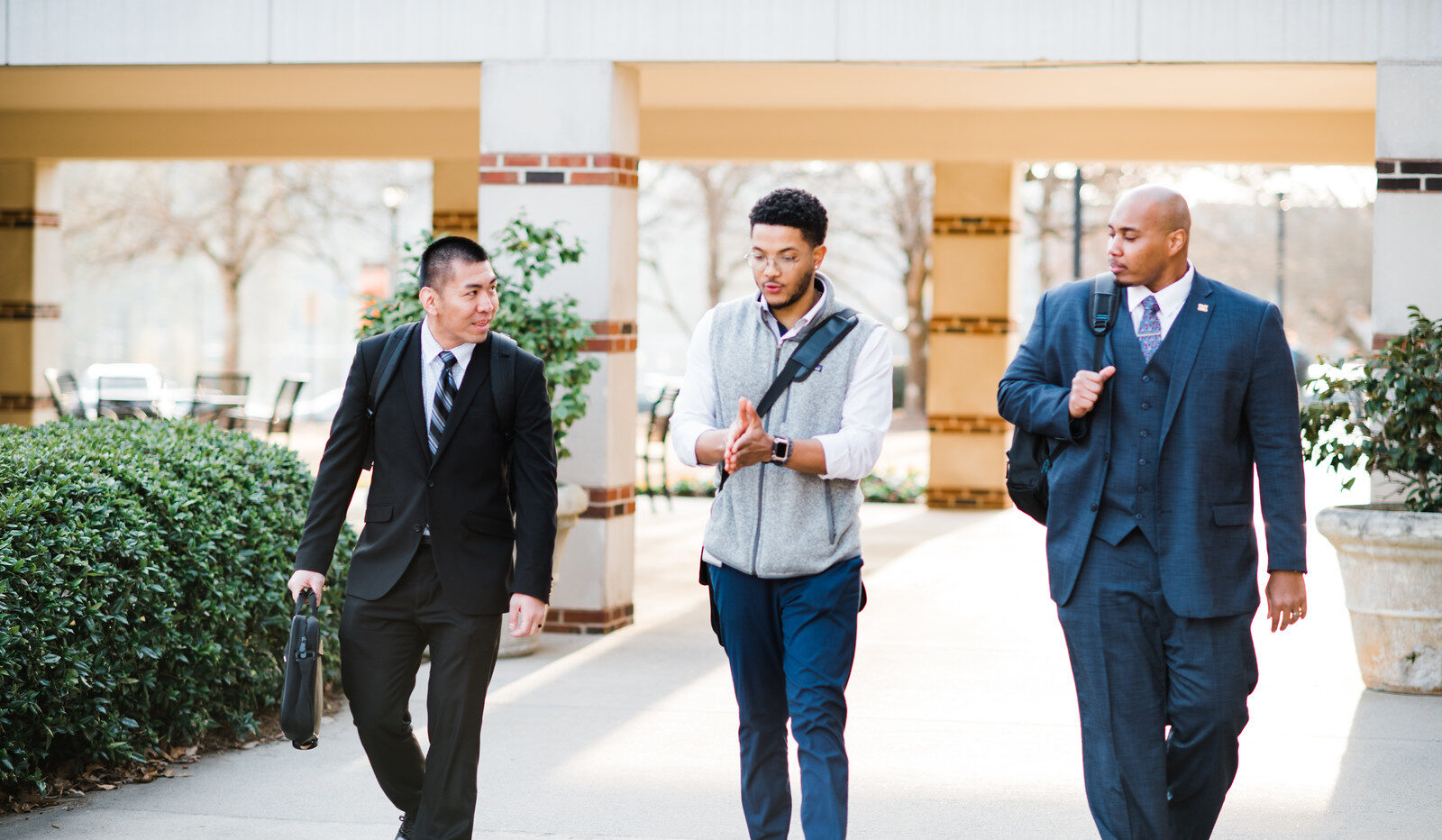 Three people walking down a sidewalk