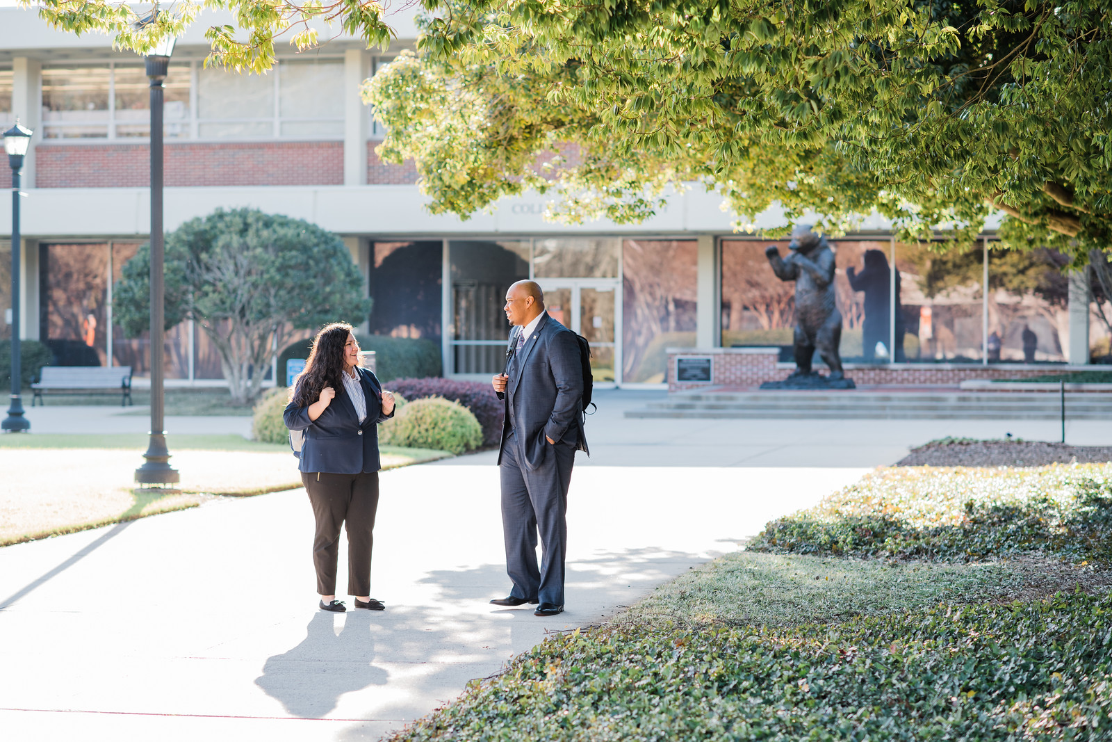 two students in professional dress standing outside on campus