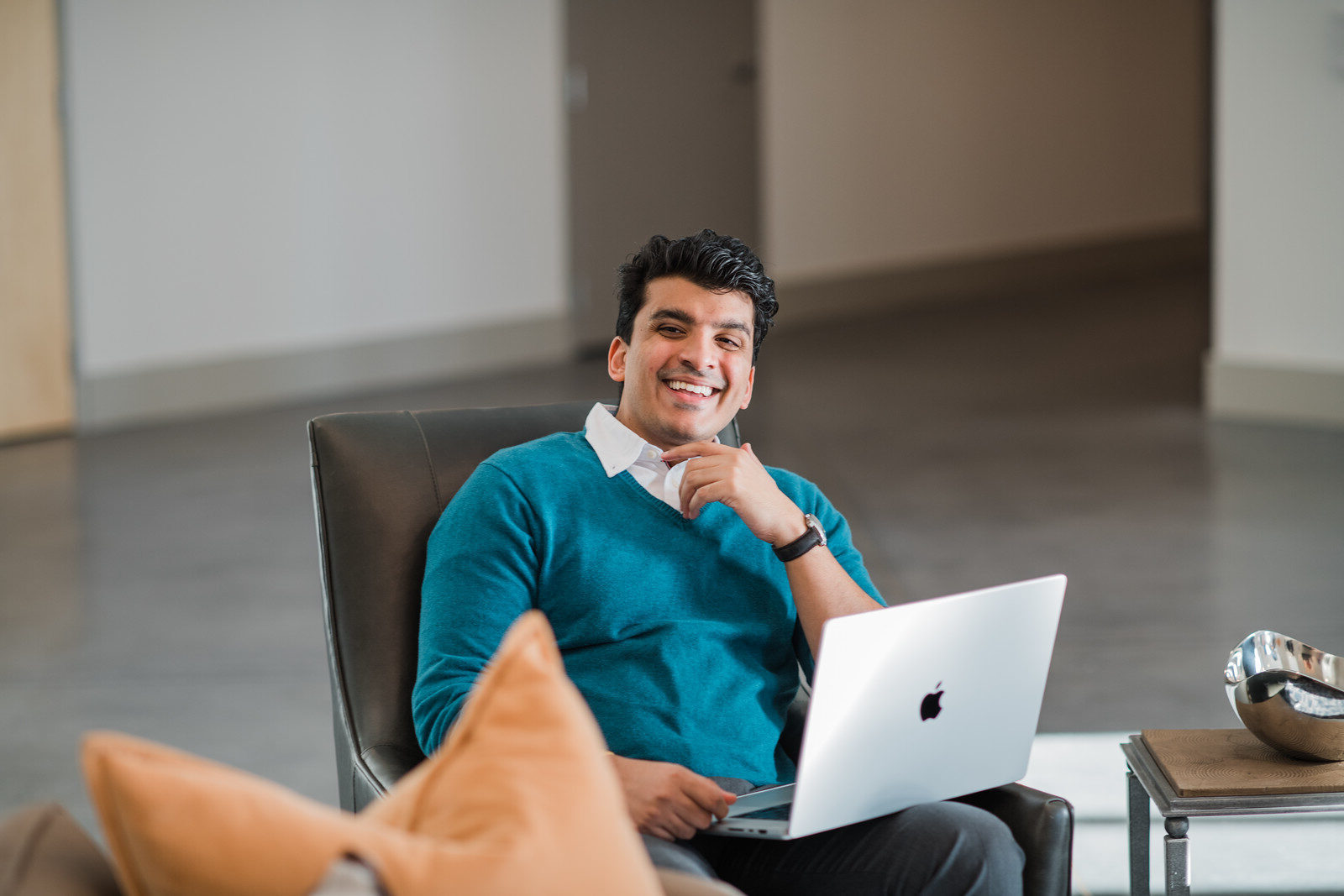 Business professional smiling with laptop in lobby