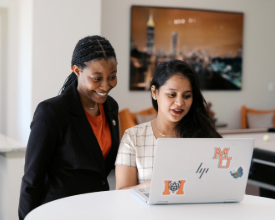 two female students looking at a laptop together